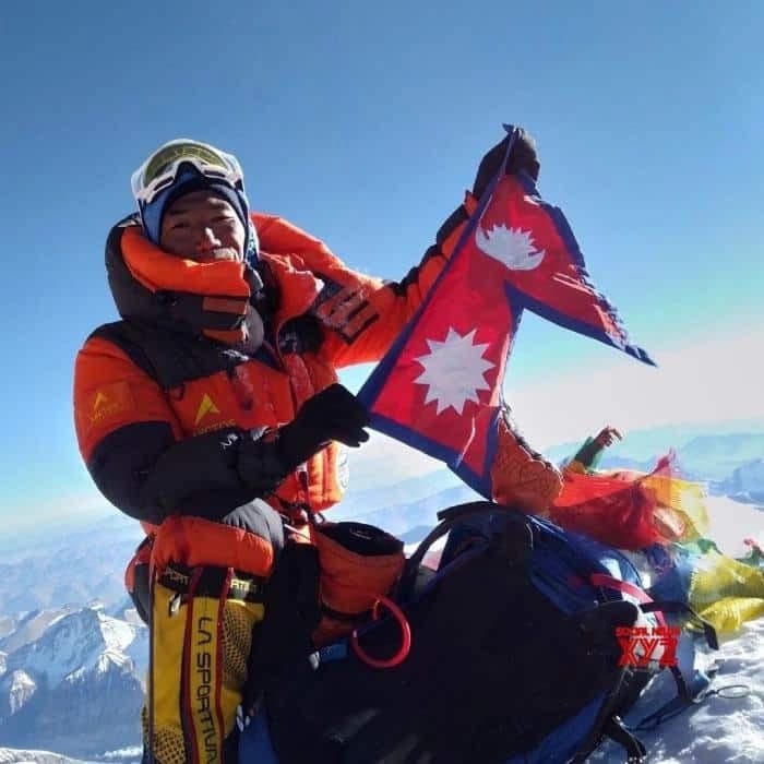 Kami Rita Sherpa holds the Nepalese flag on the mountain.