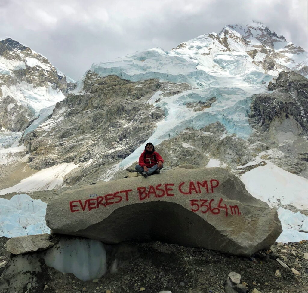 a girl sitting on the stone with a Everest Base Camp Trek script written in it in Everest, Nepal