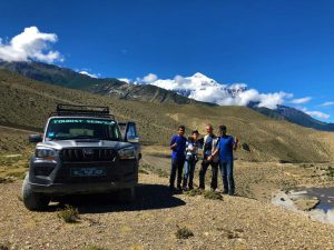 3 people posing for a photo in front of a jeep in Upper Mustang